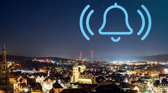 Blick über Esslingen bei Nacht, Alarmglocke als Icon im Bild.